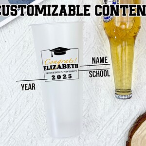 May include: A clear plastic tumbler with a black and gold graduation design. The tumbler has the text "Congrats! ELIZABETH PRINCETON UNIVERSITY 2025" on it. The tumbler is sitting on a white surface. There is a text box for "NAME", "SCHOOL", and "YEAR".
