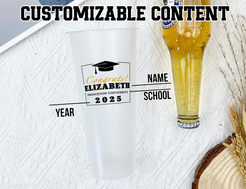 May include: A clear plastic tumbler with a black and gold graduation design. The tumbler has the text "Congrats! ELIZABETH PRINCETON UNIVERSITY 2025" on it. The tumbler is sitting on a white surface. There is a text box for "NAME", "SCHOOL", and "YEAR".