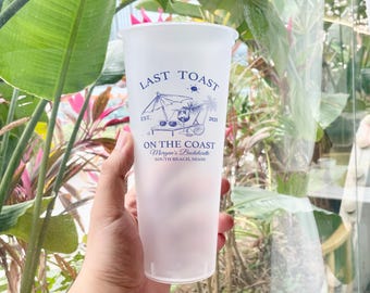 May include: White plastic tumbler with a blue and black design that says "Last Toast" and "On the Coast Morgan's Bachelorette South Beach, Miami" with a palm tree and a person wearing sunglasses on a beach chair.