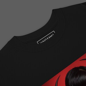 May include: Black t-shirt with a red and black graphic design. The graphic features a stylized image of a person with black hair and a red background. The text "JUNOTAMA" is printed in white on the neck label.