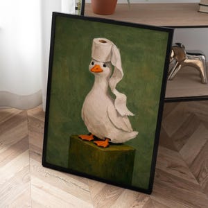 May include: A framed painting of a white duck with an orange beak and feet standing on a green block. The duck has a roll of white toilet paper balanced on its head, with a single sheet of paper draped down the side of its body against a green background.