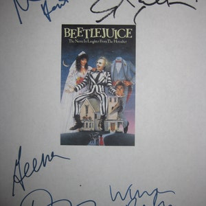 Puede incluir: Un fondo blanco con cinco firmas en tinta azul y negra. Las firmas son de Michael Keaton, Geena Davis, Winona Ryder, Alec Baldwin y Catherine O'Hara. Las firmas están sobre un fondo blanco con un póster de película para la película Beetlejuice. El póster presenta el título "Beetlejuice: The Name in Laughter from the Hereafter" e imágenes de los personajes principales.