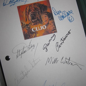 May include: A white sheet with multiple signatures in blue and black ink. A small, square image of the movie "Cujo" is in the center. The image features a large dog and a woman.