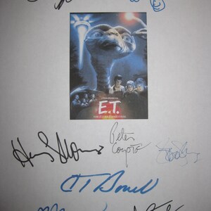 May include: A movie poster for E.T. the Extra-Terrestrial, featuring the alien's face and the film's title. The poster is surrounded by multiple signatures in black and blue ink, likely from the cast and crew.