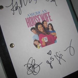 May include: A script for the television show "American Housewife" featuring the show's title and cast. The script is signed by multiple people with black ink. The script is held in a black binder.