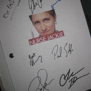 May include: A white sheet of paper with multiple signatures in black and blue ink. The image of a woman with the text "NURSE JACKIE" is visible. The paper is held together with black binder rings.