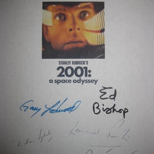 以下が含まれることがあります： スタンリー・キューブリック監督の映画「2001年宇宙の旅」のポスター。宇宙ヘルメットをかぶった男性のクローズアップが特徴。スタンリー・キューブリックとゲイリー・ロックウッドを含む、複数の人物のサイン入り。