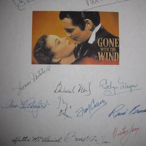 May include: A page with a film still from "Gone With the Wind" featuring Clark Gable and Vivien Leigh. The page is covered with signatures in blue and red ink, including "Clark Gable" and "Vivien Leigh".