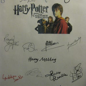 Puede incluir: Una hoja blanca con el título "Harry Potter y la Cámara de los Secretos" e imágenes de personajes. La hoja está cubierta de firmas en varios colores, incluyendo azul, negro y rojo.