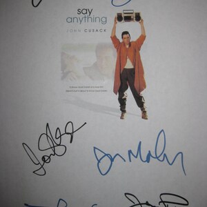 Puede incluir: Un cartel promocional de la película "Say Anything" con John Cusack sosteniendo un radiocasete. El cartel está firmado en varios colores. El título de la película y el nombre del actor están impresos en el centro.