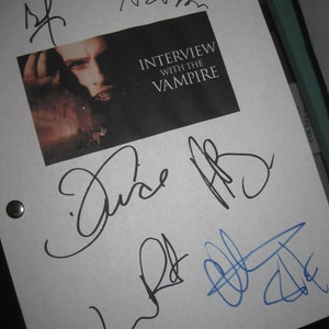 Può includere: Una pagina bianca con firme nere e blu. Le firme includono "Anne Rice", "Jude Law" e "Brad Pitt". La pagina presenta anche un poster del film in bianco e nero per "Intervista col vampiro".
