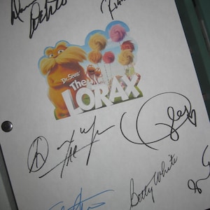 Może przedstawiać: Biała kartka papieru z wieloma podpisami czarnym i niebieskim tuszem. W centrum znajduje się kolorowa naklejka z filmu Dr. Seussa The Lorax. Podpisy wydają się być autografami.
