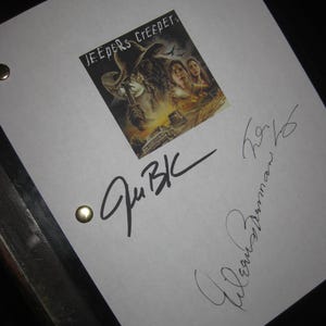 May include: A white sheet of paper with the movie poster for "Jeepers Creepers" affixed to the top. The poster features a menacing figure in a hat. The paper is signed with black ink and secured with brass fasteners.