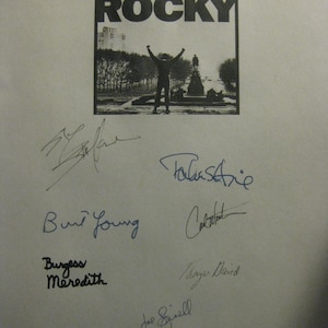 Puede incluir: Una fotografía en blanco y negro del cartel de la película "Rocky" con el lema "Toda su vida fue una apuesta de un millón a uno."  El cartel presenta una foto de Sylvester Stallone como Rocky Balboa con los brazos en alto en señal de victoria.  El cartel está firmado por varios actores de la película, entre ellos Sylvester Stallone, Talia Shire, Burt Young, Carl Weathers, Burgess Meredith y Joe Spinell.