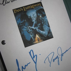 Puede incluir: Una hoja blanca con el cartel de la película "El laberinto del fauno" pegado. El cartel presenta una ilustración en tonos azules de una criatura. La hoja está firmada con tinta negra y azul.