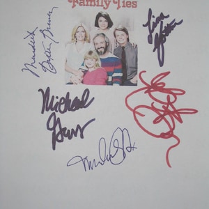May include: A signed photograph featuring the cast of "Family Ties." The image shows a group of five people, with the show's title in a stylized font above them. Several signatures in various colors surround the central image.