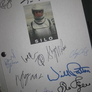 May include: A white script page for the movie "Silo" with multiple autographs in black, blue, and purple ink. The autographs include "Tom Riley", "Ferdie F", "David Oyelowo", "Morgan", "Will Patton", "Glen Fogel", and "Greg Silverman".