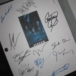 Könnte beinhalten: Ein weißes Blatt mit zahlreichen Unterschriften in schwarzer und blauer Tinte. Ein kleines Filmplakat für "Scream" befindet sich in der Mitte des Blattes. Die Unterschriften variieren in Größe und Stil.