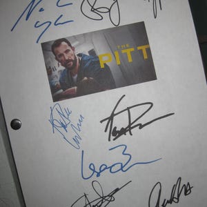 May include: A white sheet with multiple signatures in blue and black ink. A small image in the center reads "THE PITT" with a man's face. The sheet is held together with two black metal fasteners.