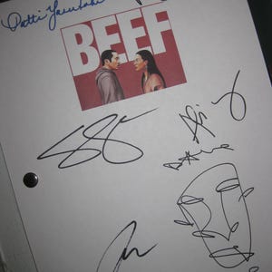 May include: A white sheet of paper with the word "BEEF" in large red letters, with an image of two people facing each other. The paper is covered in signatures, including "Patti Yasutake" and "Ashley Park".