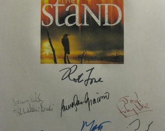 May include: A page with multiple signatures, including "Stephen King" and "Rot Fore." The center features a book cover with the title "The Stand" and an image of a figure in a desolate landscape.