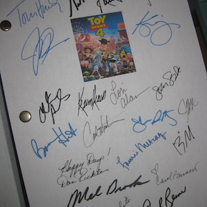 May include: A white sheet with multiple signatures in black and blue ink, surrounding a small image of the "Toy Story 4" movie poster. The signatures vary in style and size, with some including short messages.