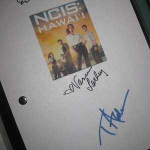May include: A white sheet of paper with the NCIS: Hawai'i show poster and multiple signatures in black and blue ink. The poster features a group of people in front of a sunset.