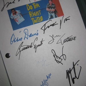 May include: A white sheet of paper covered in signatures in black and blue ink. A small image with the text "Do The Right Thing" is in the centre. The signatures are from various people.