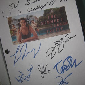 May include: A white paper with a color image from "The Summer I Turned Pretty" and multiple signatures in blue and black ink. The image shows a woman in a swimsuit by a pool. The title is in red.