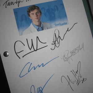 May include: A white paper with multiple signatures in black and blue ink. A small image of a man in a white coat is in the center, with the words "Good Doctor" printed on the image. The paper is held together with two silver metal fasteners.