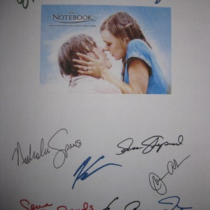 Puede incluir: Una hoja de papel blanca con varias firmas en tinta negra, azul, roja y verde. Las firmas son del reparto de la película "The Notebook". El póster de la película está en el fondo. El póster muestra una pareja besándose bajo la lluvia. El texto del póster dice "The Notebook - With every great love comes a great story."