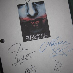 Puede incluir: Una hoja de papel blanca con un cartel de película y varias firmas. El cartel presenta un rostro con labios cosidos y el texto "30 Days of Night". Las firmas son en tinta negra y azul.