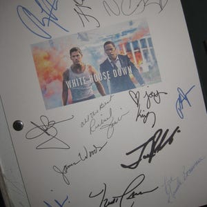 May include: A white page covered in signatures in blue and black ink. A film poster for "White House Down" is in the centre, showing two men. The page is held together with two black metal fasteners.