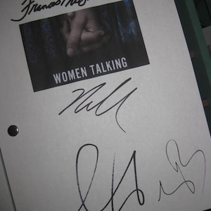 May include: A white paper with the title "WOMEN TALKING" printed on a black rectangle. The paper has multiple signatures in black ink, including one that reads "Frances McDormand". Two black metal fasteners are visible.
