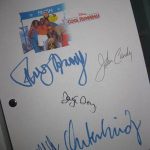 Op de afbeelding: Een wit papier met handtekeningen en een "Cool Runnings" filmposter. De poster toont een groep mensen in kleurrijke outfits. De handtekeningen zijn in blauwe en zwarte inkt. Het Disney-logo is zichtbaar.