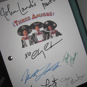 May include: A white sheet of paper with signatures from the cast and crew of the movie "Three Amigos!" The signatures include John Landis, Steve Martin, Martin Short, and others. The movie title is written in red, yellow, and blue letters.