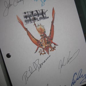 May include: A white sheet of paper with the title "Heavy Metal" printed in black and silver. The paper is signed by John Candy, Bill Bonham, John Vernon, and Susan Roman.