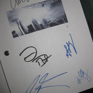 May include: A white paper with the title "CHRONICLE" and a cityscape image, featuring multiple signatures in black and blue ink. The paper is held together with two black rivets.