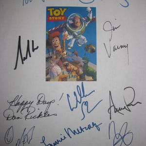 May include: A white sheet of paper featuring a "Toy Story" movie poster with multiple signatures in blue and black ink. The poster shows Woody, Buzz Lightyear, and other characters. Signatures include "Tom Hanks" and "Don Rickles".