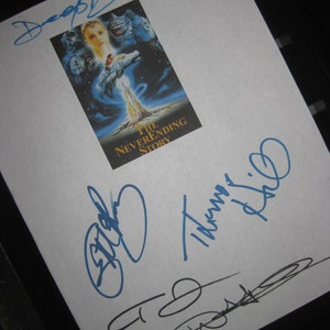 May include: A white sheet of paper with three blue and black signatures. The signatures are for "Daryl", "Barret", and "Thomas Riddle". The paper also has a small image of the movie poster for "The Neverending Story" with the text "The Neverending Story" printed below the image.