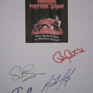 May include: A poster for "The Rocky Horror Picture Show" with a woman on a red lip-shaped couch. The poster includes the text "Give Yourself Over to Absolute Pleasure." Several signatures are visible below the poster.