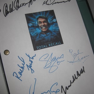Puede incluir: Un papel blanco con el cartel de la película "Total Recall" con Arnold Schwarzenegger. El papel está cubierto de firmas en tinta negra y azul. El cartel está en el centro de la página.