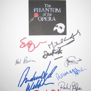 May include: A black square featuring the title "The Phantom of the Opera" with a red rose and a white mask. The image is covered in signatures in various colors, including red, blue, and black.