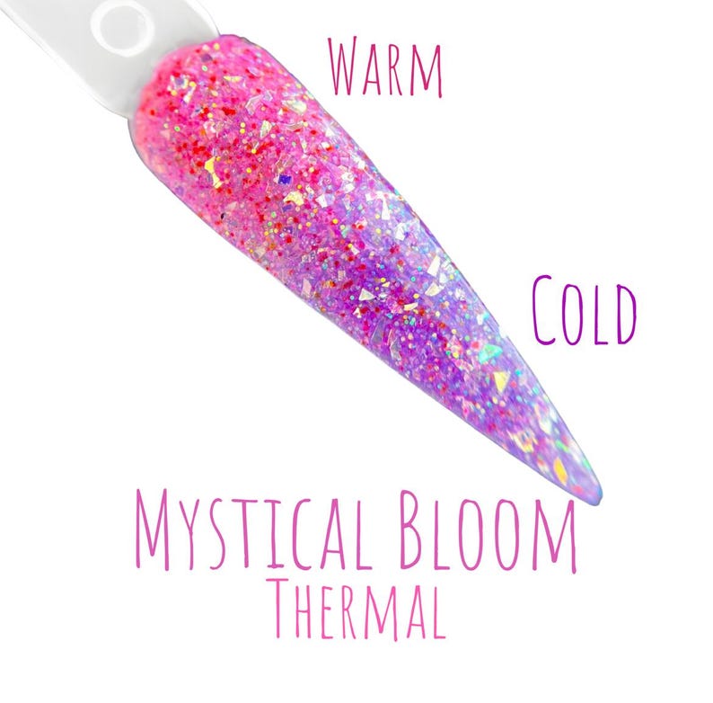 May include: A nail swatch with a gradient effect, transitioning from warm pink to cool purple. The nail is covered in glitter, with the words "WARM" and "COLD" on either side. The text "MYSTICAL BLOOM THERMAL" is also present.