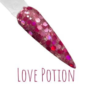 May include: A close-up of a pink and red glitter nail polish with a holographic finish. The polish is called "LOVE POTION".