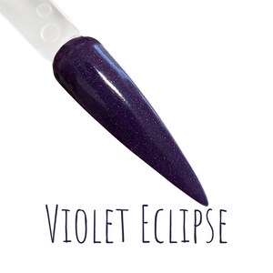 May include: A nail swatch displays a deep purple color with a glittery finish. The nail is shaped into a long, pointed tip. The text "VIOLET ECLIPSE" is written in a handwritten style font below the nail.