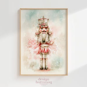May include: A watercolor-style illustration of a nutcracker soldier wearing a white uniform with gold accents, a tall hat adorned with red flowers, and a mustache. The figure holds a red and white drum, set against a soft, light-colored background.
