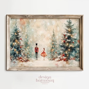 May include: A framed watercolour print with a wooden border. The image shows a nutcracker and a ballerina standing between two Christmas trees adorned with lights and red baubles. Snow falls in the background, creating a winter scene.
