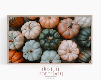 May include: A framed wall art print featuring a collection of pumpkins in various muted shades including sage green, dusty orange, cream, and soft peach. The pumpkins are arranged closely together, filling the frame with their rounded shapes.