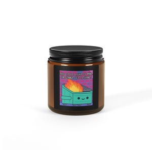Peut inclure: Un pot en verre brun avec un couvercle noir. L'étiquette présente un dessin animé d'une benne à ordures en feu avec le texte "THIS LITTLE LIGHT OF MINE, I'M GONNA LET IT SHINE."